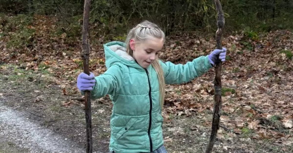 Kind op een bospad houdt twee wandelstokken vast