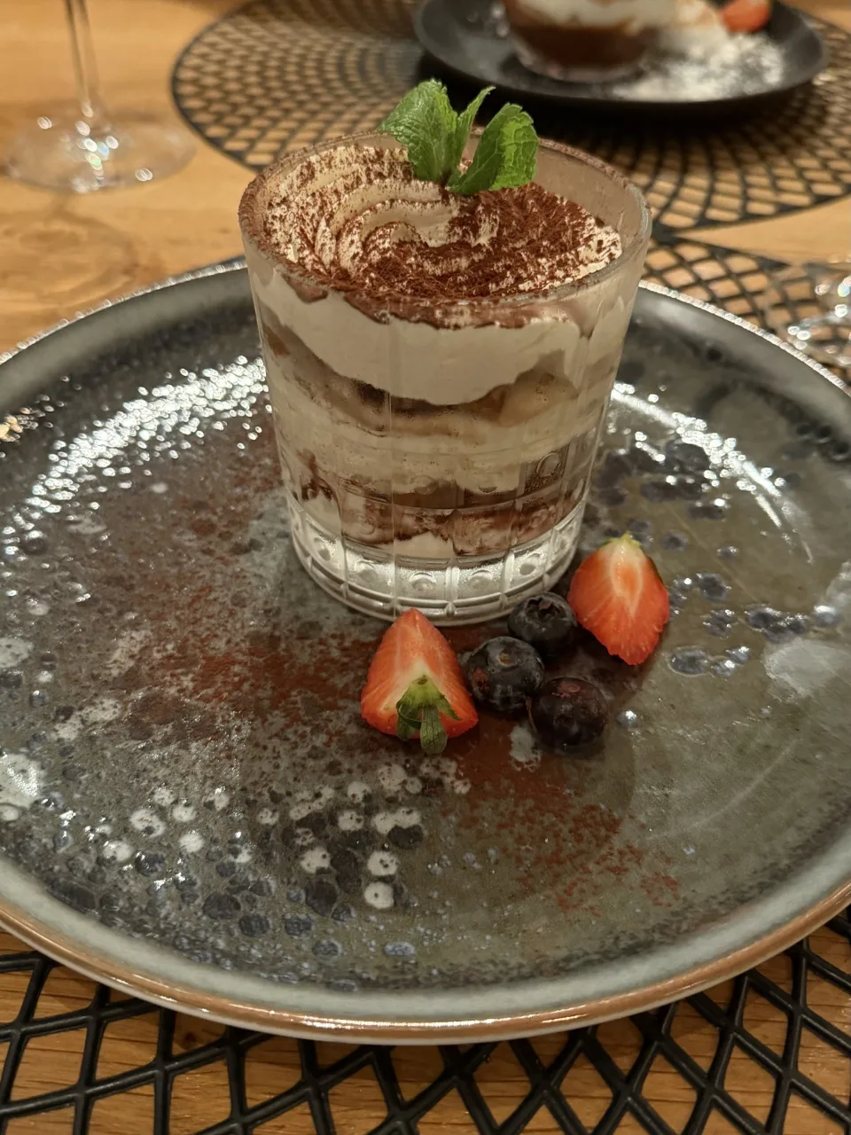 Dessert in een glas met cacao en munt, met aardbeien en blauwe bessen op het bord, bij De ProefTuin