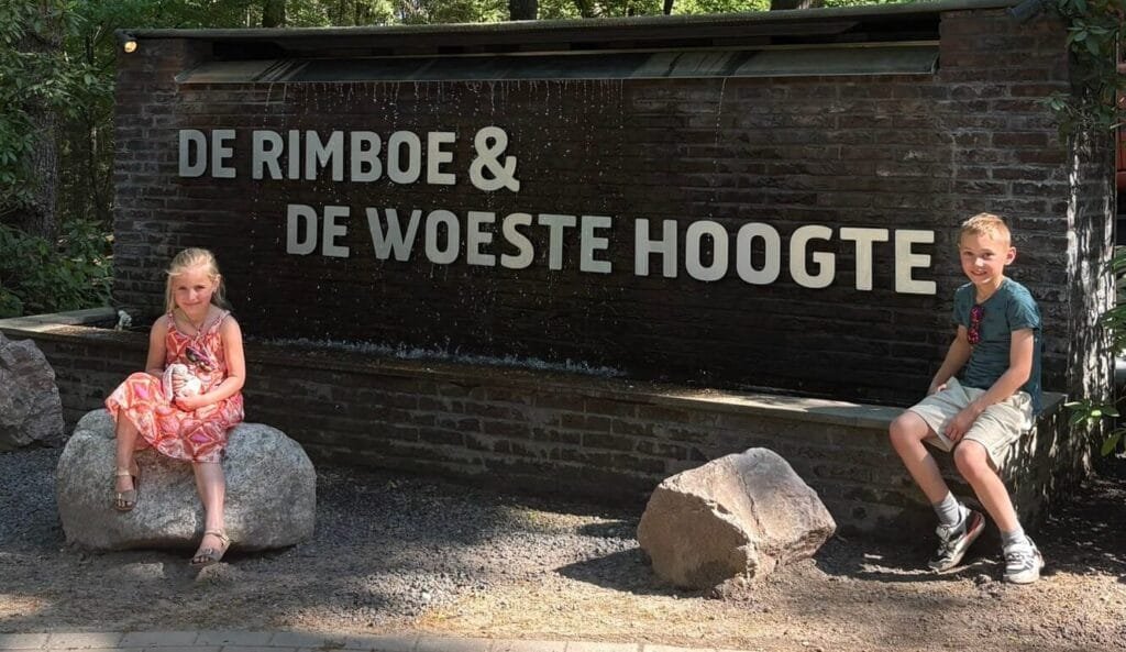 Kinderen spelen bij het bord van vakantiepark De Rimboe en De Woeste Hoogte in Hoenderloo