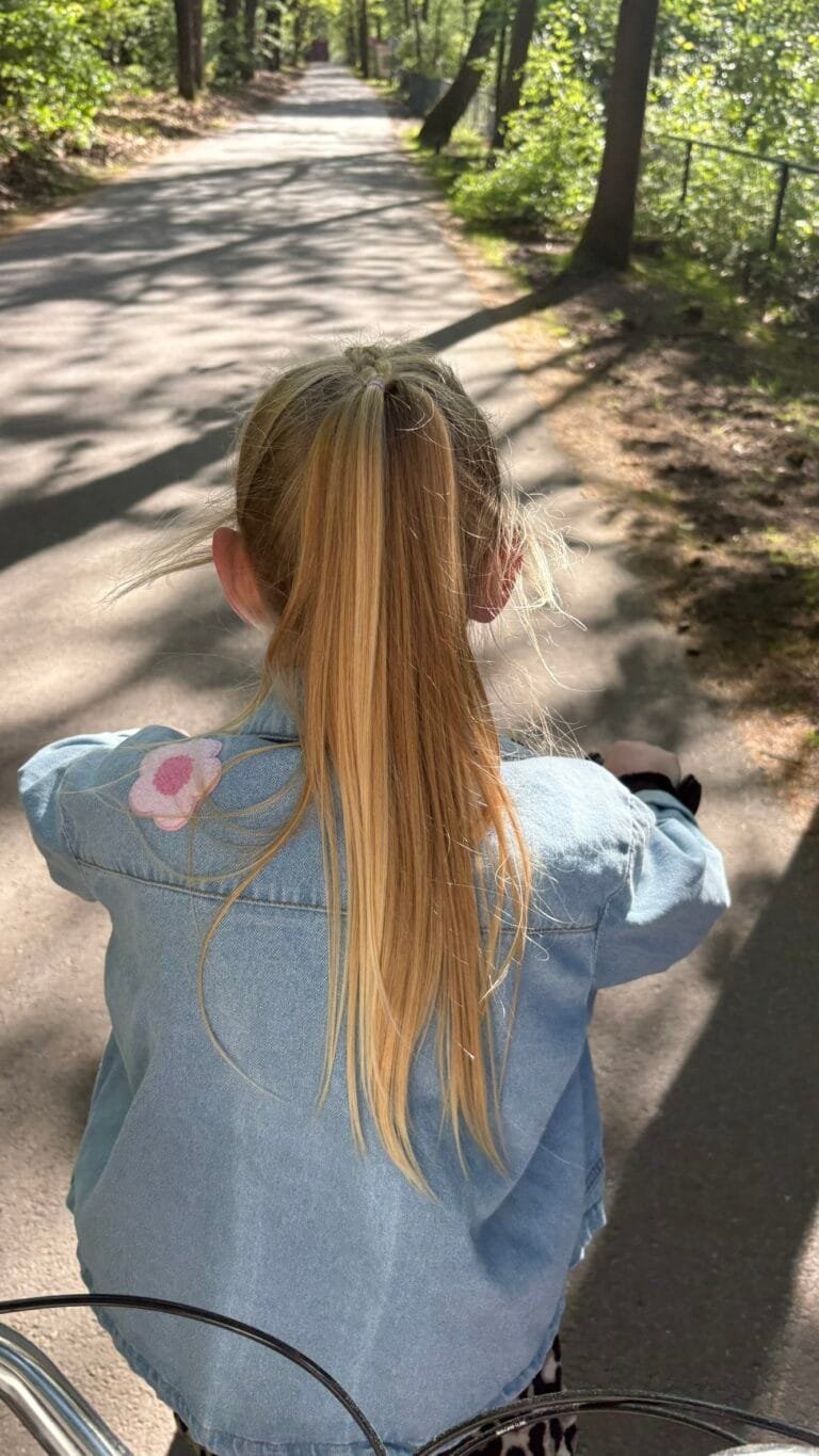 Kind fietst over een zonnig bospad op de Veluwe