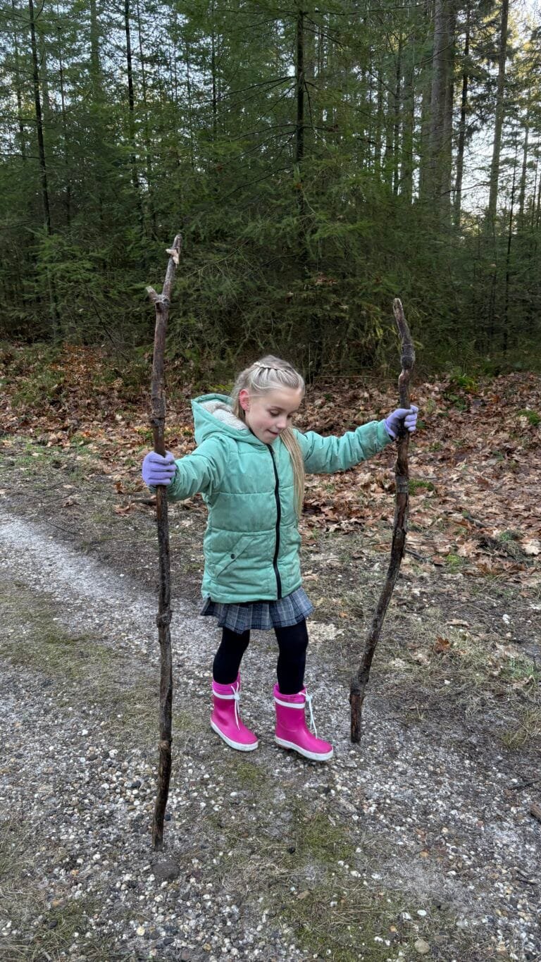 Meisje met twee wandelstokken op een bospad op de Veluwe