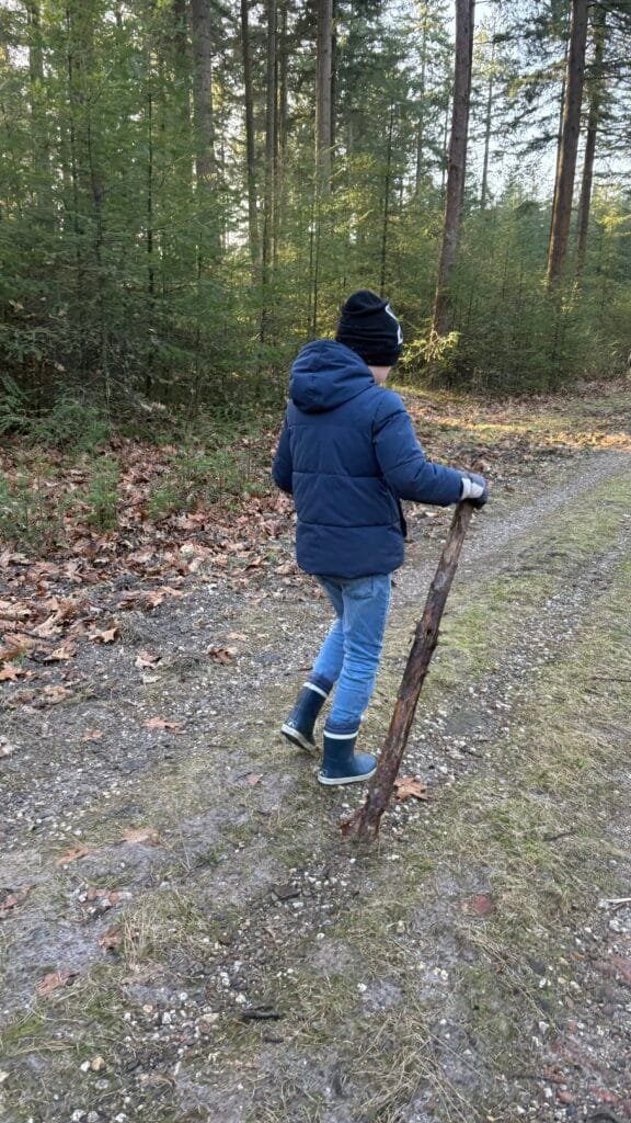 Kind wandelt met een stok over een bospad op de Veluwe